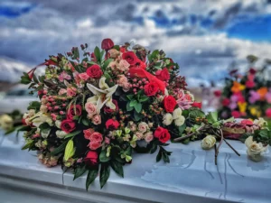 Composition florale élégante déposée sur le dessus d'un cercueil blanc.
