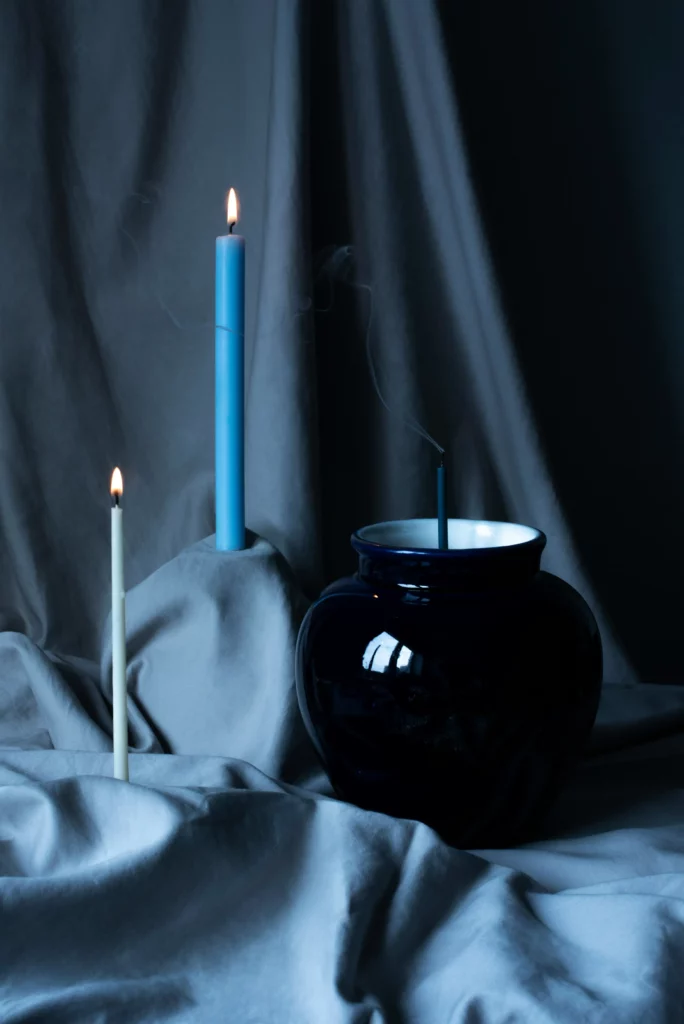 Urne cinéraire bleue entourée de bougies allumées et d'encens.