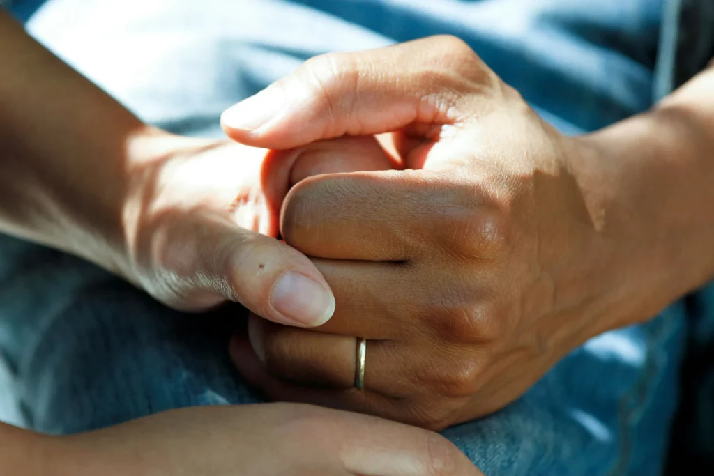 Gros plan sur deux mains serrées symbole de réconfort et de présence.